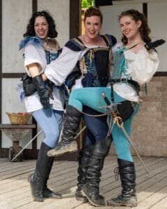 Three costumed Renaissance performers posing with swords