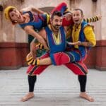 Three acrobats in colorful costumes performing balancing act